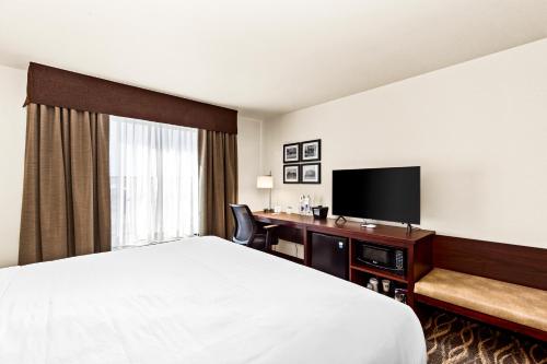 a hotel room with a bed and a desk with a television at Cobblestone Hotel & Suites - Superior Duluth in Superior