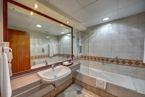 a bathroom with a sink and a tub and a mirror at Al Manar Grand Hotel Apartment in Dubai