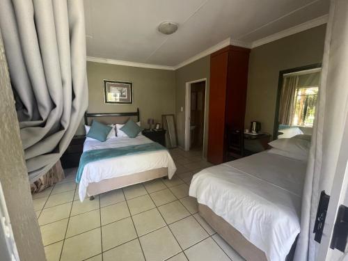 a bedroom with two beds and a window at Toro Guest House in Rustenburg