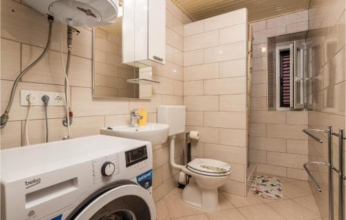 a bathroom with a washing machine next to a toilet at 2 Bedroom Stunning Home In Susak in Susak