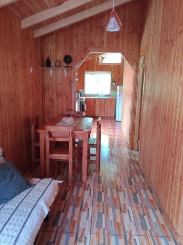 ein Esszimmer mit einem Tisch und einer Küche in der Unterkunft Cabaña Gloria in Coñaripe