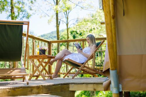 a woman sitting in a chair on a deck at Glamping Bagrem in Jablanica