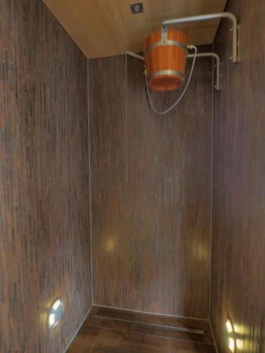 a shower with an orange bucket on a wooden wall at Aparthotel Alpinresort Damüls in Damuls