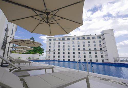 a hotel swimming pool with chairs and an umbrella at Haile Grand Addis Ababa in Addis Ababa