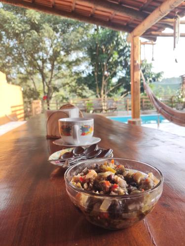 a bowl of food on a wooden table with a cup at Pousada Pato Mergulhão in Vargem Bonita