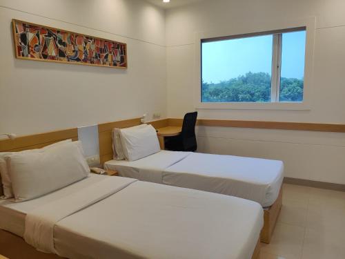 Habitación de hotel con 2 camas y ventana en Mango Grove Hotel, en Chandīgarh