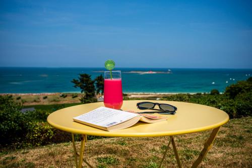 a yellow table with a book and a drink on it at Domaine Buhez Nevez in Trélévern