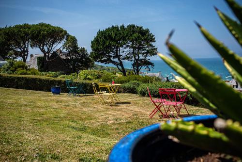 un groupe de tables et de chaises dans un champ avec l'océan dans l'établissement Domaine Buhez Nevez, à Trélévern