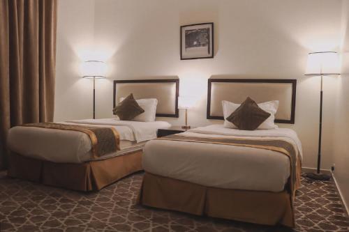 two beds in a hotel room with two lamps at فندق البروج in Jazan