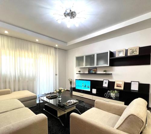 ein Wohnzimmer mit einem Sofa, einem TV und einem Tisch in der Unterkunft Spacious family-friendly apartment in the heart of Bllok in Tirana