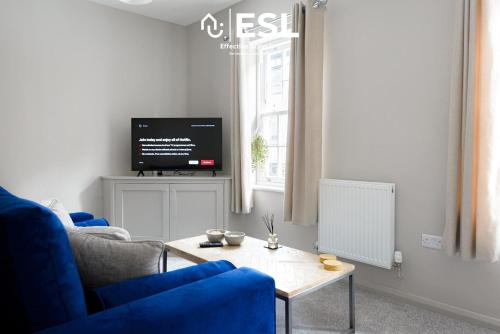 ein Wohnzimmer mit einem blauen Sofa und einem Tisch in der Unterkunft Comfy Modern 2 Bedroom Duplex Apartment with Sun Terrace in Shrewsbury