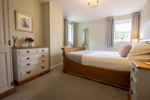 a bedroom with a bed and a dresser and a window at 1 Riverside Cottage in Burnsall