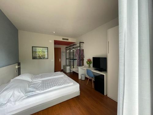 a bedroom with a bed and a desk and a television at Hotel Al Caval in Torri del Benaco