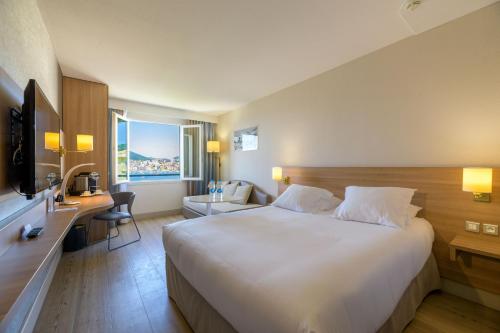a hotel room with a large bed and a desk at Best Western Plus Ajaccio Amirauté in Ajaccio