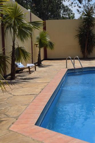 a swimming pool with palm trees next to a building at Stasumo House Arusha in Arusha