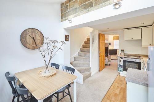 eine Küche und ein Esszimmer mit einem Tisch und einer Uhr an der Wand in der Unterkunft Host & Stay - Waterlily Cottage in Great Ayton