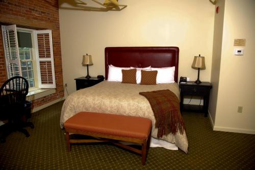 a bedroom with a large bed and two windows at The Common Man Inn & Restaurant in Claremont