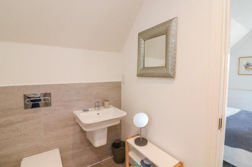 a white bathroom with a sink and a mirror at Driftwood, 29 Furzedown Road in Kingsbridge