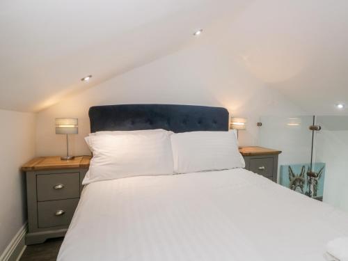 a bedroom with a bed with white sheets and two lamps at Annabels Loft in Hawes