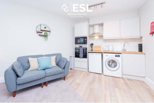 ein Wohnzimmer mit einer blauen Couch und einer Küche in der Unterkunft Studio 2, Second Floor Town Centre Apartment in Shrewsbury