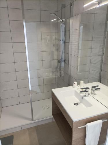 une salle de bain avec un lavabo et une douche dans l'établissement Hotel Astoria, à Saint-Étienne