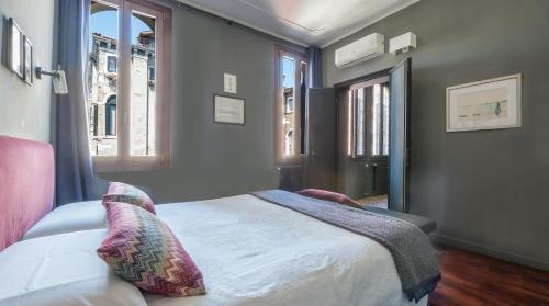 een slaapkamer met een bed en 2 ramen bij Stylish Renovated Apartment In The Heart Of The City in Venetië