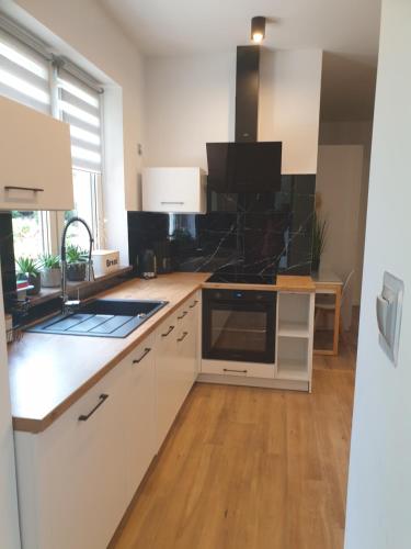 a kitchen with white cabinets and a wooden floor at VILLA MILA Apartamenty in Karpacz