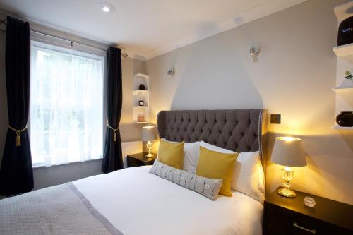 Un dormitorio con una cama con almohadas amarillas y una ventana en Avari Apartments - Winchester Collection en Londres