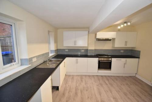 een keuken met witte kasten en een zwart aanrecht bij Cheerful 2-bedroom home with off street parking in Blackpool
