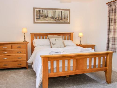 um quarto com uma cama de madeira e uma cómoda em Camden Cottage em Kidderminster