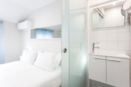 a white bathroom with a bed and a sink at Urban City in Aveiro