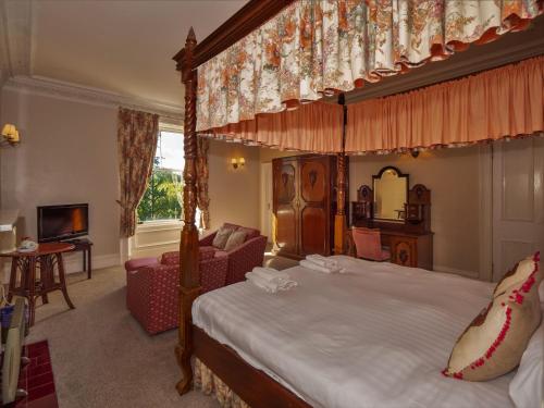 1 dormitorio con cama con dosel y sala de estar. en Clonyard House Hotel en Dalbeattie