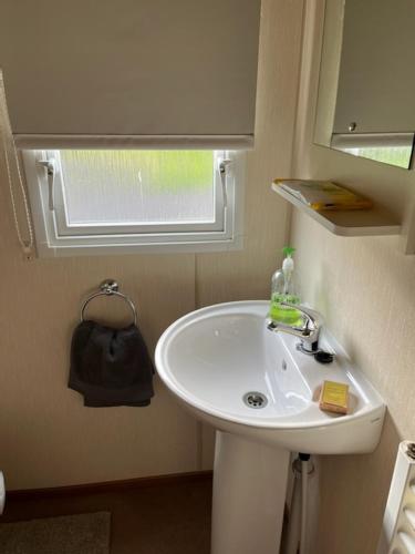 uma casa de banho com um lavatório branco e uma janela em Coyles retreat em Stranraer