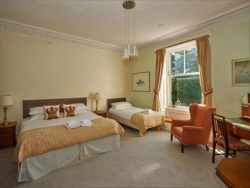a bedroom with two beds and a desk and a window at Clonyard House Hotel in Dalbeattie