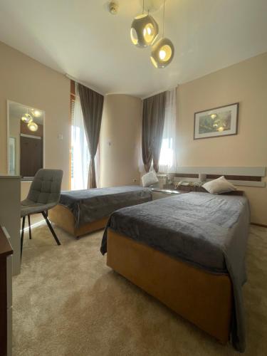 a hotel room with two beds and a chair at Freya SPA Apartments in Niš