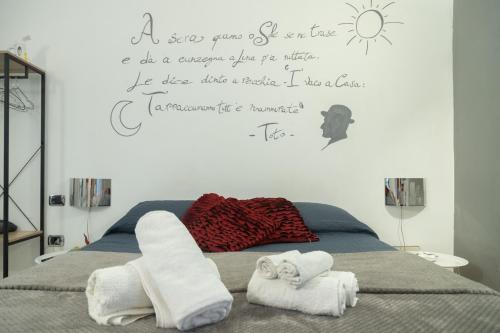 una camera da letto con un letto con asciugamani e scritte a muro di Totò Style Apartment a Napoli