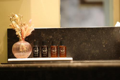 three bottles of hot sauce next to a vase of flowers at Hotel Biskajer by CW Hotel Collection - Adults Only in Bruges