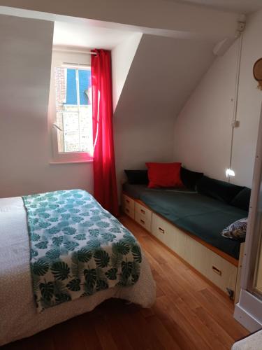 een slaapkamer op zolder met een bed en een raam bij La P'tite Normande in Villerville