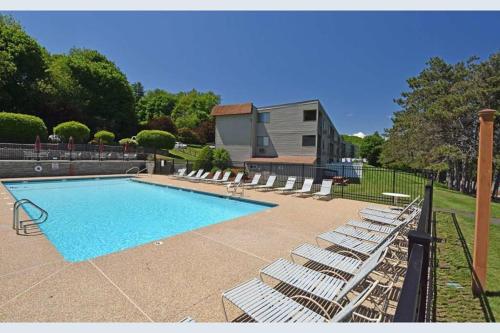 a swimming pool with lounge chairs and a house at 2 Bdrm Condo walking distance to Weirs Beach in Laconia