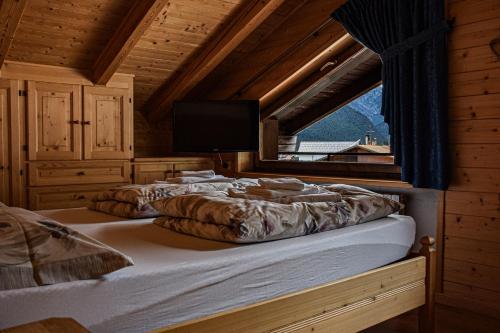 two beds in a room with a window at Appartamento Mainardi in Auronzo di Cadore