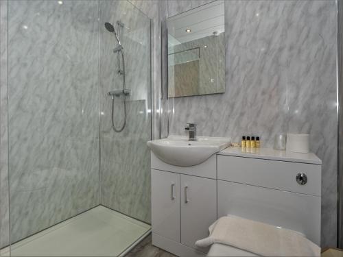 a bathroom with a shower and a sink and a mirror at Clonyard House Hotel in Dalbeattie