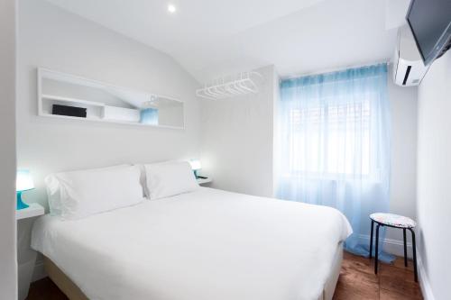 a white bedroom with a white bed and a window at Urban City in Aveiro