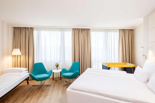 Habitación de hotel con 2 camas, mesa y sillas en NH Berlin Alexanderplatz en Berlín