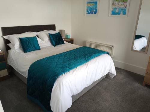 a bedroom with a large bed with a blue blanket at Contemporary one bed studio. Sea views and parking in Westward Ho