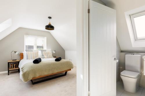 a white bedroom with a bed and a toilet at Ashtree House in Barton on Sea