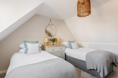 two beds in a room with white walls at Ashtree House in Barton on Sea