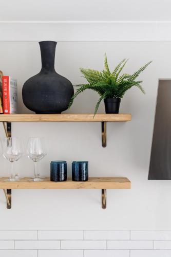 a shelf with a vase and two glasses and a plant at Ashtree House in Barton on Sea