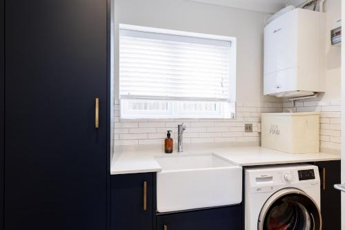 a kitchen with a sink and a washing machine at Ashtree House in Barton on Sea