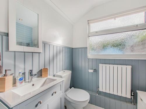 a bathroom with a toilet and a sink and a window at Kiwi Cottage in Whitstable