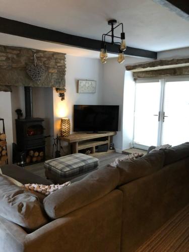 a living room with a brown couch and a fireplace at Mistletoe Cottage in Foulridge